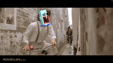 a man is riding a bike down a narrow street with movieclips.com on the bottom