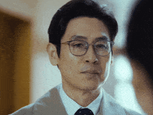 a close up of a man wearing glasses and a suit and tie