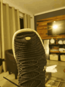a black shoe with a yellow rubber sole is sitting on a table
