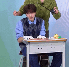 a man is sitting at a desk wearing gloves and a sweater .
