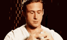 a man in a white shirt is praying with his eyes closed and his hands folded .
