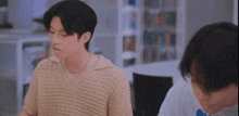 a man in a sweater is sitting at a table with another man .