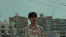 a man wearing a floral shirt stands in front of a city skyline