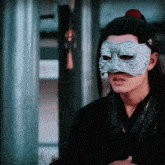 a man wearing a silver mask is standing in a room .