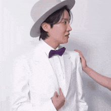 a man in a white suit and hat is being helped by a woman