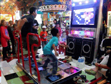 a boy in a blue shirt is dancing in front of a machine that says ' rhythm ' on it