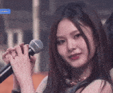 a close up of a woman holding a microphone in front of a sign that says ' kirasi '