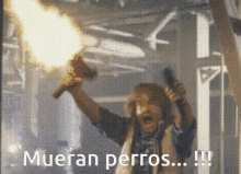 a man holding a torch and a gun with the words mueran perros !!! below him