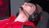 a man wearing headphones and glasses is laying down on a chair that says ' gigabyte ' on it