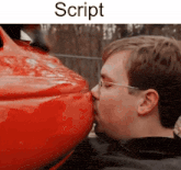 a man is kissing the side of a red car with the word script above him .