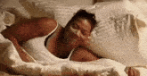 a woman in a white tank top is sleeping in a bed with a pillow that has the word pulp on it