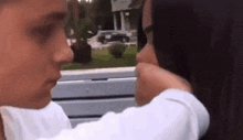 a man and a woman are touching each other 's faces on a bench .