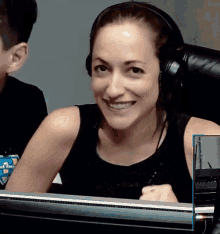 a woman wearing headphones is smiling while sitting in front of a computer screen