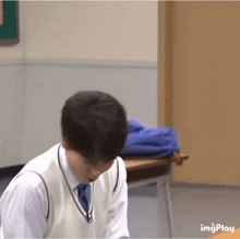 a man in a vest and tie is sitting at a desk in a classroom ..