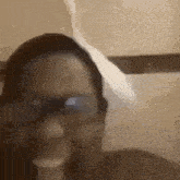 a close up of a person wearing glasses and smoking a cigarette in a bathroom .