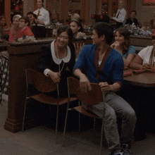a man in a blue sweater sits next to a woman in a black dress at a restaurant