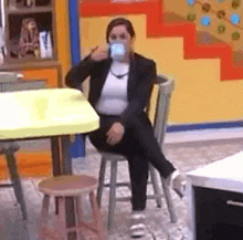 a woman in a suit is sitting on a chair drinking from a cup