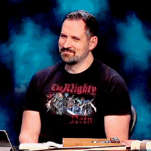 a man wearing a black t-shirt that says the mighty on it