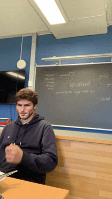 a man sitting in front of a blackboard that says ' a / a / a ' on it