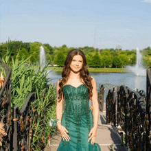 a woman in a green dress stands on a bridge over a body of water