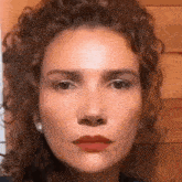 a woman with curly hair and red lipstick is making a face .
