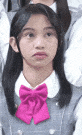 a girl with long hair and a pink bow tie