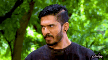 a man with a beard and mustache is wearing a black shirt with the word ortika on the sleeve