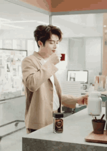 a man in a tan suit drinking from a cup