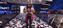 a wrestler is walking down a ramp holding a wrestling belt .