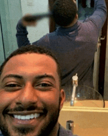 a man is smiling in front of a bathroom mirror