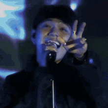 a man singing into a microphone with a peace sign