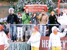 a group of people standing in front of a sign that says macy 's celebrates the holiday seas