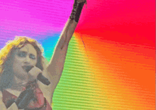 a woman singing into a microphone with a colorful background