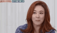 a woman with red hair is wearing a blue sweater and making a funny face
