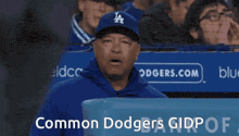 a man in a dodgers hat stands in front of a sign that says common dodgers