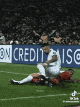 two soccer players on a field with a sign that says on credit