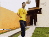 a man in a yellow shirt with a smiley face on it is kicking a soccer ball