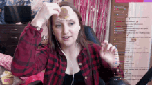 a woman wearing headphones and a red plaid shirt is holding a cupcake in front of her face