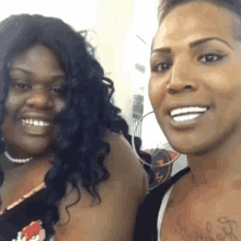 two women are posing for a picture and one of them has a tattoo on her chest that says " i love you "