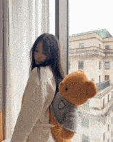a woman is holding a teddy bear in her back