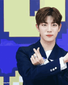 a young man in a suit is making a heart shape with his fingers