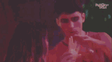 a man in a red tank top is drinking from a glass with big brother brasil written on the bottom right