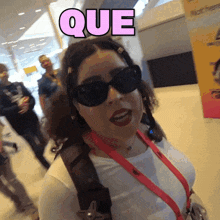 a woman wearing sunglasses and a lanyard with the word que above her head