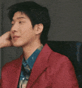 a close up of a person touching a man 's face while he is wearing a red jacket .