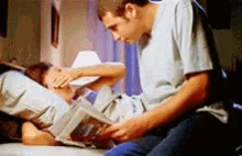 a man is reading a book to a child who is laying on a bed