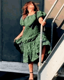 a woman in a green dress standing on a set of stairs
