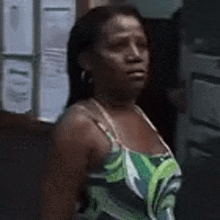 a woman in a green and white dress is standing in front of a door .