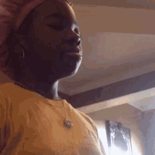 a woman wearing a pink hat and a necklace is standing in a room .