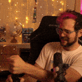 a man with pink hair is sitting in a dxr racer chair