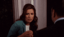a woman in a blue jacket is talking to a man in a black suit .